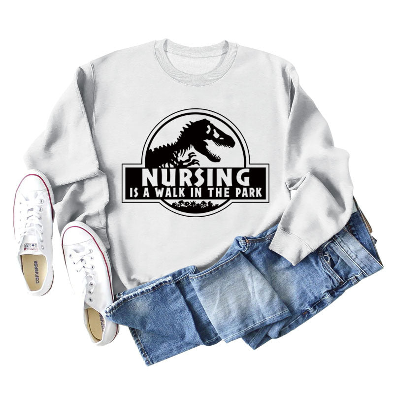 Nursing Is A Walk In The Park Langarm-Sweatshirt mit Rundhalsausschnitt, Dinosaurier-Print